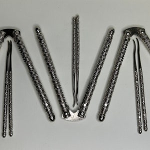 May include: A set of silver-colored nutcrackers and picks. The nutcrackers have textured handles and a hinged design. The picks are slender and designed to extract the nut meat. The tools are arranged on a white surface.