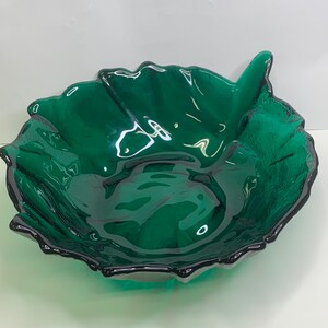 Op de afbeelding: Een decoratieve, smaragdgroene glazen kom in de vorm van een blad. De kom heeft een textuuroppervlak en een donkere, geschulpte rand. De kom is ontworpen als decoratief stuk.