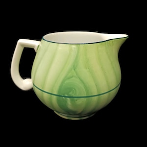Może przedstawiać: Ceramiczny dzbanek z białym uchwytem i wylewką. Dzbanek jest pomalowany zielono-białym wzorem w wiry i zieloną linią pośrodku. Wnętrze jest białe z zieloną obwódką.