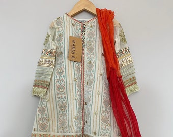 May include: A white and gold girls' dress with a red dupatta. The dress has a floral pattern and a gold embroidered border. The dupatta is made of a sheer fabric and has a fringe trim.