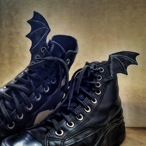 Pair of black bat wings made of leather with metal wires that help the wing to bend, attached to pair of black laced boots