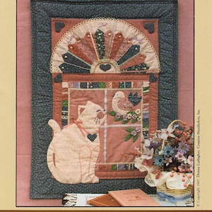 May include: A quilting pattern for a wall hanging titled "Kitty's Window" from the Country Charm Series. The pattern features a cat, a bird, and a flower basket. The finished size is 23 inches by 32 inches.