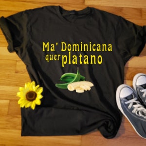 May include: Black t-shirt with the text "Ma' Dominicana quer platano" in yellow letters and a graphic of green plantains and yellow banana slices.