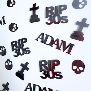 Può includere: Decorazioni nere ritagliate sparse su sfondo bianco. Le decorazioni includono forme di teschio, lapidi e testo che recita "RIP 30s" e "ADAM". Il tema è probabilmente legato a un memoriale o ad Halloween.