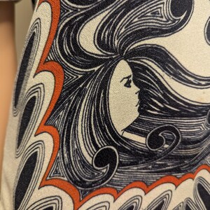 Pu&ograve; includere: Primo piano di un tessuto color crema con un motivo ripetuto. Il design presenta il profilo di una donna con capelli neri fluenti ed elementi decorativi arancioni e neri. Il tessuto sembra far parte di un capo d'abbigliamento, con un'estetica vintage.