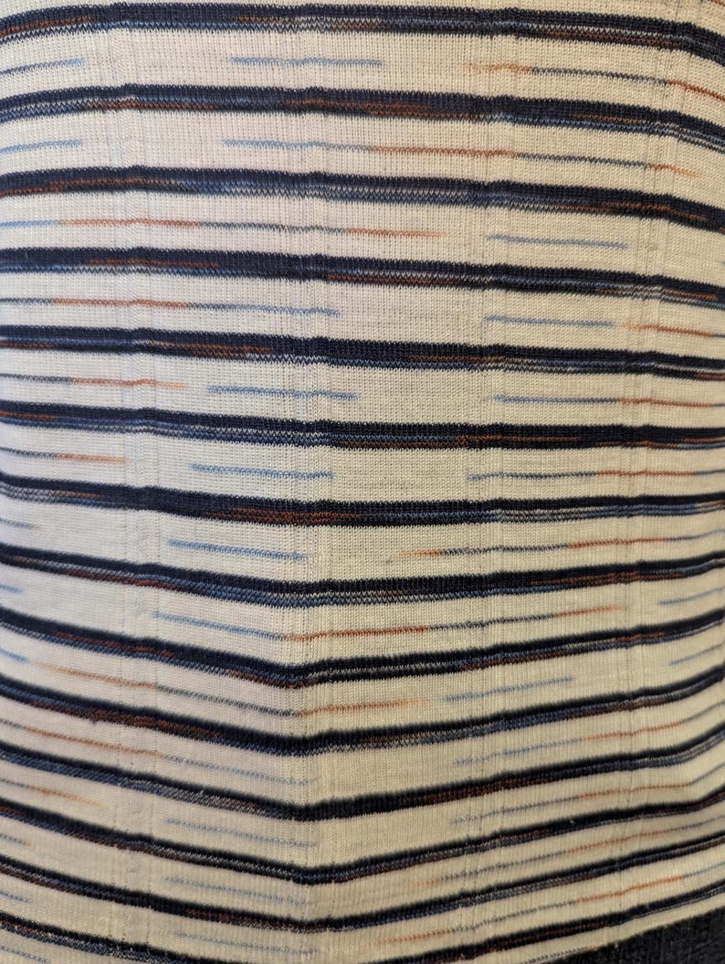 May include: White fabric with thin horizontal stripes in navy blue, light blue, and brown.
