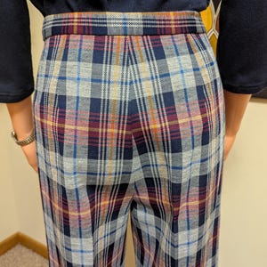 Op de afbeelding: Een wijde broek met een geruit patroon in tinten blauw, grijs, rood en oranje. De broek heeft een hoge taille en een ontspannen pasvorm.