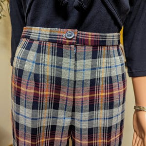 Op de afbeelding: Hoge taille geblokte broek met knoopsluiting. De broek is een mix van blauwe, grijze, rode en gele ruitjes.