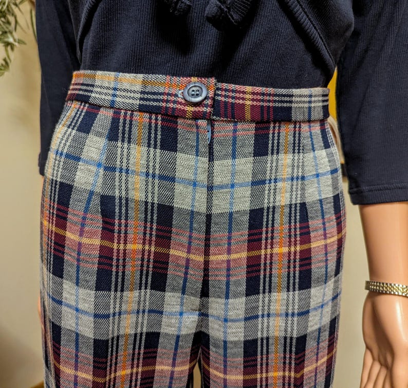 Op de afbeelding: Hoge taille geblokte broek met knoopsluiting. De broek is een mix van blauwe, grijze, rode en gele ruitjes.