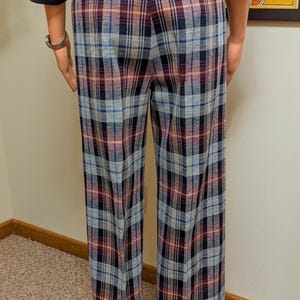 Op de afbeelding: Een broek met ruitjes in blauw, grijs, oranje en bordeauxrood. De broek heeft een wijde pijp en een omslagen zoom.