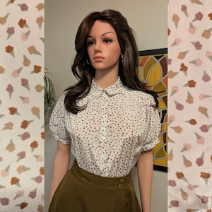 May include: A short-sleeved button-down blouse featuring a white base with a repeating pattern of small brown and pink ice cream cone shapes, paired with a solid olive green high-waisted skirt that has two visible buttons at the waistband.