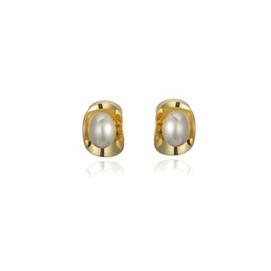 Könnte beinhalten: Ein Paar goldfarbene Ohrstecker, jeweils mit einer glänzenden, oval geformten Perle. Die Ohrringe haben ein modernes Design mit einer geschwungenen, offenen Fassung. Die Ohrringe werden auf weißem Hintergrund präsentiert.