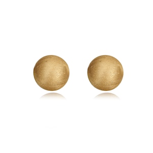 May include: A pair of spherical stud earrings with a brushed gold finish. Each earring features a textured, matte surface that catches the light, creating a subtle glow across the round, metallic form. The design is simple, circular, and uniform.