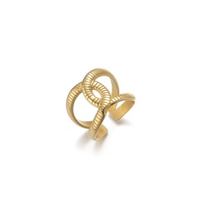 May include: A gold-colored ring with a unique, intertwined design. The ring features a textured, ridged surface and an open cuff style. The design is abstract and geometric, with multiple loops and curves. The ring is set against a white background.