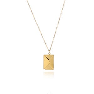 Puede incluir: Un collar dorado con un colgante en forma de sobre. El colgante es rectangular con un diseño de solapa plegada. La delicada cadena también es dorada, creando un accesorio simple pero elegante.