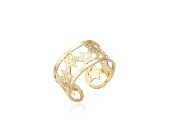 May include: A gold-coloured adjustable ring featuring a repeating star pattern. The ring has an open design with cut-out stars, creating a celestial theme. The ring is shown on a white background.