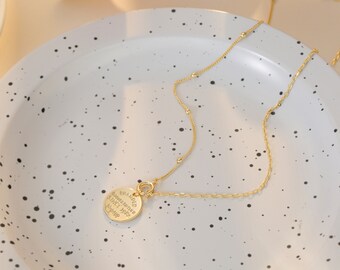 May include: A gold chain necklace with a round pendant that says "Branded Jewellery Since 1992 No. 149".