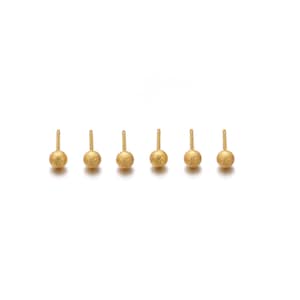 May include: A set of six gold-toned stud earrings, each featuring a small, spherical ball with a textured, glittery surface finish. The earrings are arranged in a horizontal row, showcasing the uniform round shape and the metallic gold color.