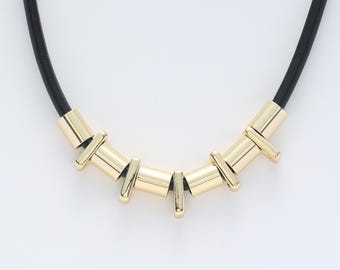 May include: A black leather choker necklace with gold-toned geometric pendant accents.