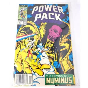 May include: A vintage comic book titled "Power Pack" with a colourful illustration. The cover art depicts a large yellow figure with a purple face, and several smaller figures in action. The text "The Coming of Numinus" is also visible.