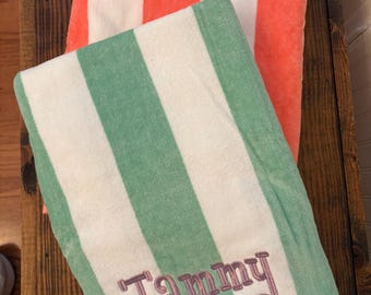 May include: Two folded rectangular towels with vertical stripes. The top towel features alternating white and bright orange stripes. The bottom towel has alternating white and light green stripes with the name Tammy embroidered in purple script.
