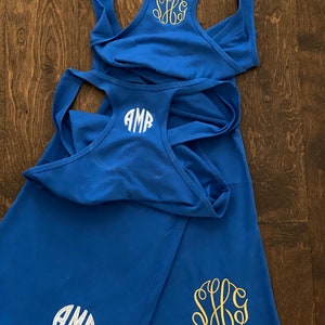 May include: Two blue tank tops with white and gold monograms. The monograms are "AMR" and "SHG".