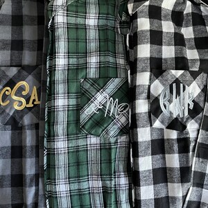 May include: Three flannel shirts with different plaid patterns. The shirts have pockets with embroidered initials: "CSA", "KM", and "BWR".