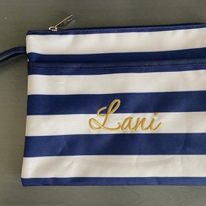 May include: A blue and white striped zippered pouch with a gold embroidered name "Lani" on the front.