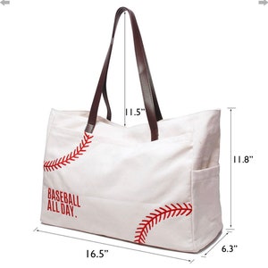 May include: White canvas tote bag with brown leather handles. The bag features red baseball stitching and the text "BASEBALL ALL DAY." The bag is 16.5 inches wide, 11.8 inches high, and 6.3 inches deep, with 11.5-inch handles.