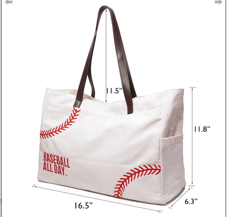 May include: White canvas tote bag with brown leather handles. The bag features red baseball stitching and the text "BASEBALL ALL DAY." The bag is 16.5 inches wide, 11.8 inches high, and 6.3 inches deep, with 11.5-inch handles.