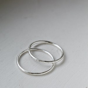 A close up of Sterling Silver stackable rings stacked onto a white background. Rings on a white wooden background.