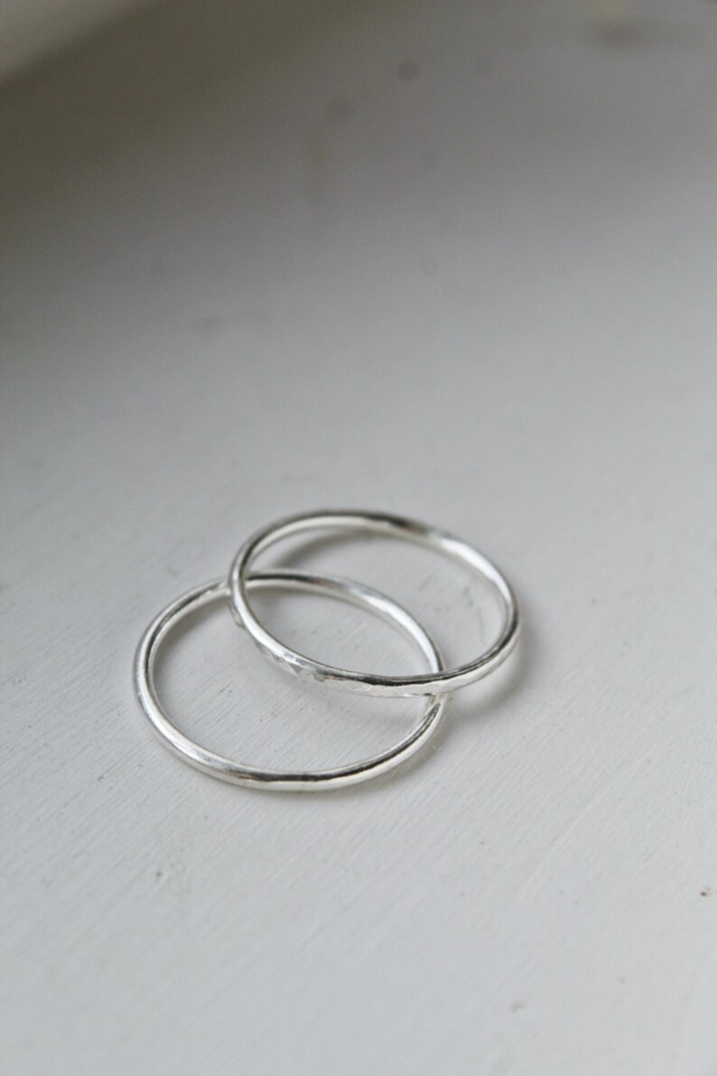 A close up of Sterling Silver stackable rings stacked onto a white background. Rings on a white wooden background.