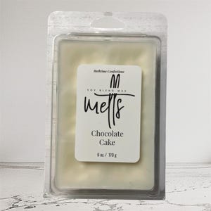 May include: A rectangular wax melt in a clear plastic clamshell. The wax is a creamy off-white color. A white label reads "Bathtime Confections" and "melts" with "Chocolate Cake" below. The label also states "6 oz. / 170 g."