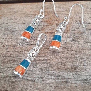 May include: A set of silver earrings and a pendant featuring a blue and orange stone with intricate filigree designs.