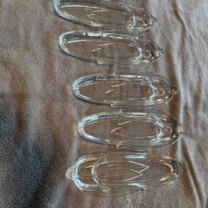 May include: A set of six clear glass corn-shaped dishes. Each dish has a detailed design mimicking corn on the cob. The dishes are oval-shaped with a textured surface, perfect for serving appetizers or small portions.