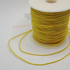 May include: A spool of bright yellow elastic cord. The cord is wound tightly around the spool and is ready to be used for crafting projects.