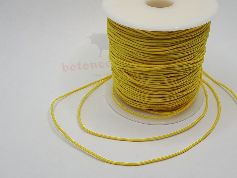 May include: A spool of bright yellow elastic cord. The cord is wound tightly around the spool and is ready to be used for crafting projects.