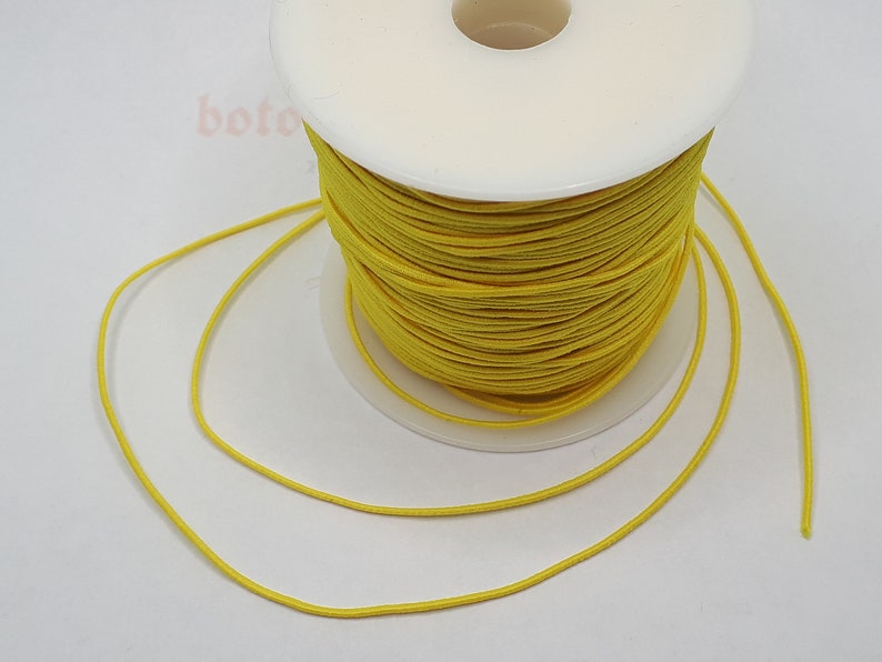 May include: A spool of bright yellow elastic cord. The cord is wound around a white plastic spool.
