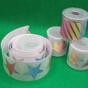 May include: Four rolls of colorful patterned washi tape. The tape is white with different designs, including stars, butterflies, leaves, and stripes.