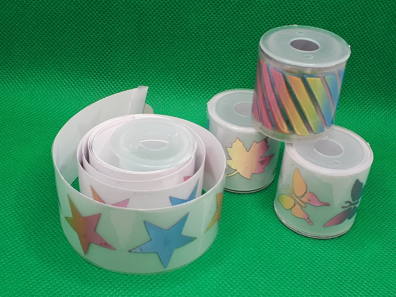 May include: Four rolls of colorful patterned washi tape. The tape is white with different designs, including stars, butterflies, leaves, and stripes.