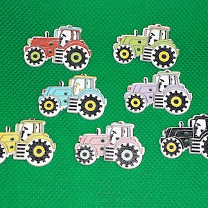 Può includere: Sette bottoni in legno a forma di trattore di diversi colori, tra cui rosso, verde, blu, viola, giallo, rosa e nero. Ogni bottone ha un contorno nero e ruote gialle.