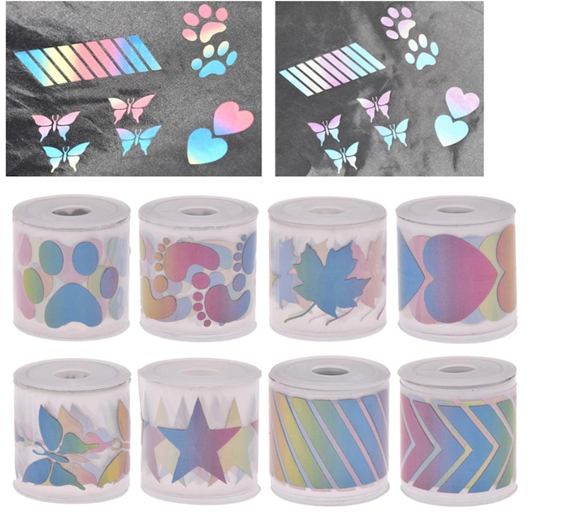 May include: Eight rolls of iridescent holographic washi tape with various designs, including paw prints, hearts, butterflies, stars, and stripes. The tape is on white spools.