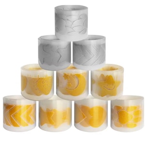 Può includere: Una collezione di candele cilindriche con vari disegni. Alcune candele presentano motivi dorati di stelle, lune e altre forme. Altre candele hanno motivi argentati. Le candele sono disposte in una formazione impilata.