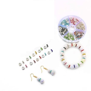 Può includere: Un set di perline di strass colorate in un contenitore di plastica, un braccialetto di perle bianche con accenti di strass colorati e un paio di orecchini dorati con accenti di perle bianche e strass.