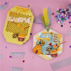 Può includere: Due etichette di carta gialle e blu con un motivo a nido d'ape e un tema di api. La prima etichetta dice "BEAUTIFUL" e la seconda etichetta dice "New day New start".