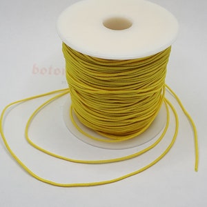 May include: A spool of bright yellow elastic cord. The cord is wound around a white plastic spool. The cord is about 1/8 inch thick.