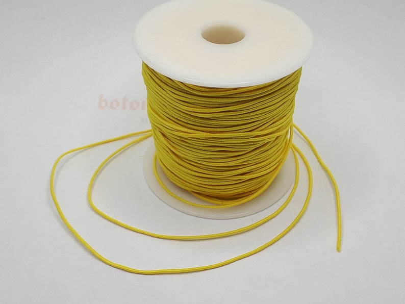 May include: A spool of bright yellow elastic cord. The cord is wound around a white plastic spool. The cord is about 1/8 inch thick.