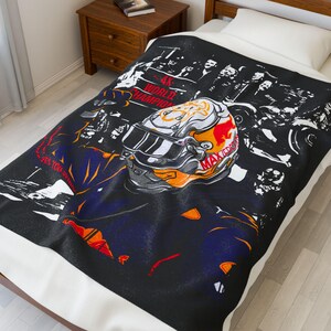 May include: Black and white throw blanket with a graphic of a race car driver wearing a helmet with the words "4X World Champion" and "Max Verstappen" on it.