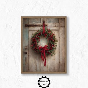 Op de afbeelding: Een ingelijste prent van een kerstkrans met rode bessen en een rood lint, hangend aan een verweerde houten deur. De krans is het middelpunt, met de deur en het frame als rustieke achtergrond. Het kunstwerk is gesigneerd "Kiamo Ko Art".