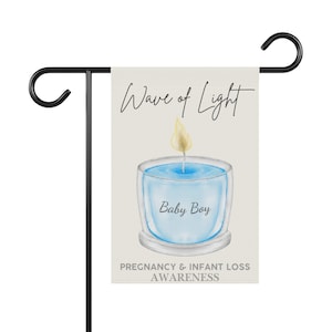 May include: A garden flag on a black metal stand. The flag displays a watercolour illustration of a blue candle with the text "Wave of Light" and "Baby Boy". The bottom of the flag reads "Pregnancy & Infant Loss Awareness".
